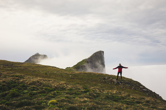 Man standing at the edge of a cliff enjoying a hike at hornstrandir peninsula  westfjord iceland overlooking the northern ocean cover in fog with head in the clouds 