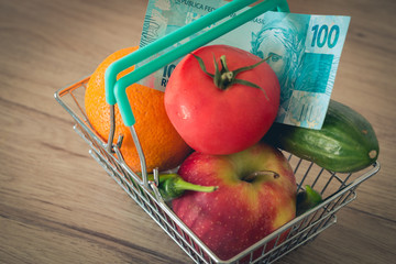 Vegetables and fruits in the shopping basket along with Brazilian money