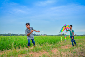 Two friends playing with kite at paddy field in the evening