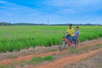 happy young local boy riding old bicycle at paddy field