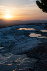 Fototapeta premium Turkey, sunset on the travertine terraces at Pamukkale (Cotton Castle), natural site of sedimentary rock deposited by water from the hot springs, famous for a carbonate mineral left by flowing water