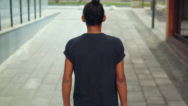 back view brunette man wearing casual t-shirt walking on the street summertime in town