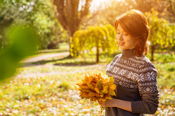 portrait of a young woman smiling in an autumn Park with leaves in her hands