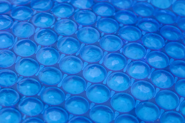 Blue cyan abstract background. Close up of blue bubble plastic used as a swimming pool insulation cover to prevent evaporation of water and to retain the heat