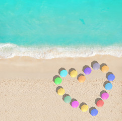 Heart shape of different color umbrellas on beach