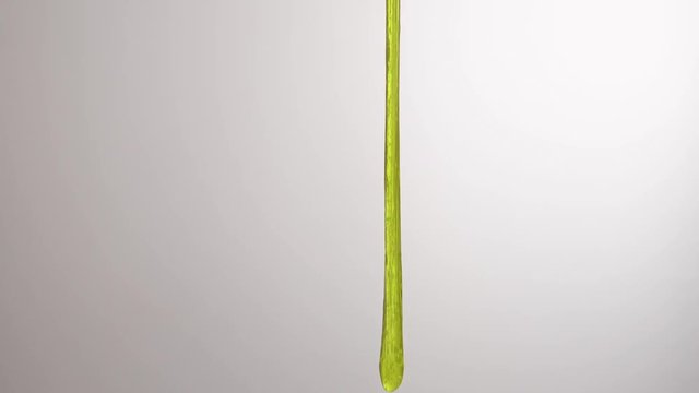 A close-up of green slime stretching and falling down. Cool mucus and liquid toy. Isolated, on white background