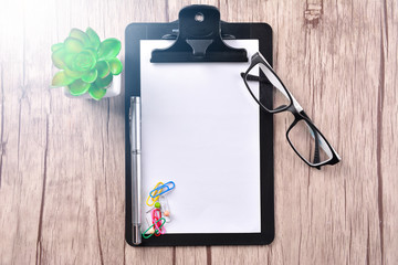 Clipboard with empty paper on wooden table