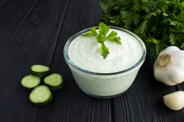 Traditional greek yogurt with cucumber on the black wooden background.Closeup.