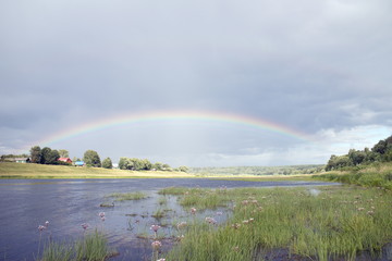 Rainbow after rain over the summer river
