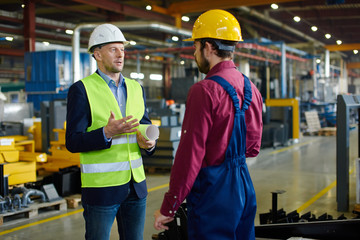 Engineers in hard hats working at the industrial plant.