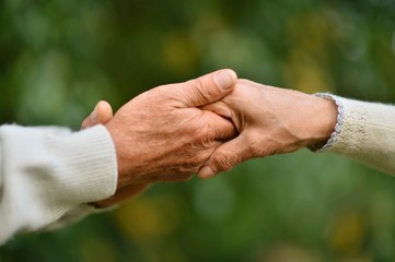 Hands held together on a natural green background