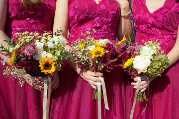 Three bridesmaids in lilac lace dresses with bouquets of fresh flowers, selective focus