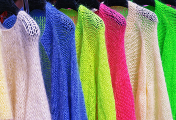 Mohair jackets bright colors on hangers in the store.