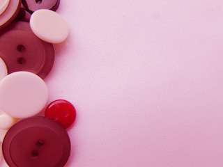 The composition of white, red and brown buttons on a pink fabric background.