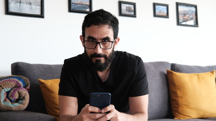 Hombre  Adulto navegando en su celular en  la sala de su casa. 