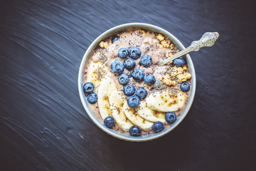 Healthy breakfast berry smoothie bowl topped with banana, granola, Blueberries and chia seeds with copy space