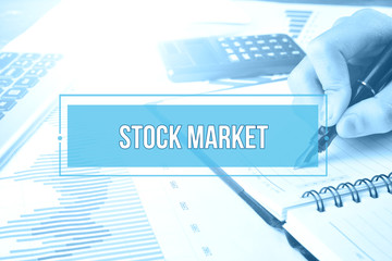 Hand writing on blank notebook with text STOCK MARKET