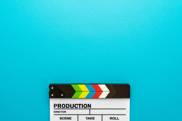 Top section of white clapperboard at the bottom of turquoise blue background with copy space. Top view photo of movie clapboard as filmmaking concept. Minimalist flat lay of film slate. - obrazy, fototapety, plakaty