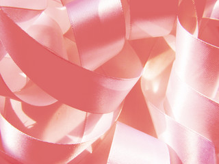 Wide pink pastel color satin ribbon lying sewing chaotic rings gentle background.