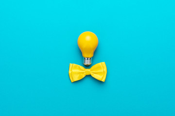 Top view photo of smart idea with yellow bulb and bow tie. Minimalist flat lay image of bow tie and...