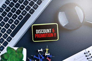 Keyboard with magnifying glass on black background with text DISCOUNT & PROMOTION