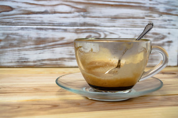 empty cup of espresso and a silver coffee spoon on a wooden table close up
