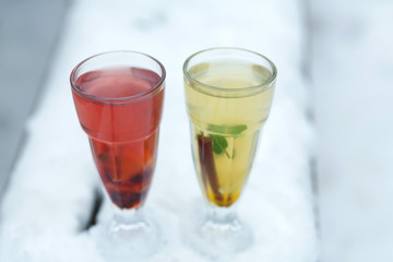 two glasses of hot vitamin tea on winter snowy bench. winter hot seasonal drinks