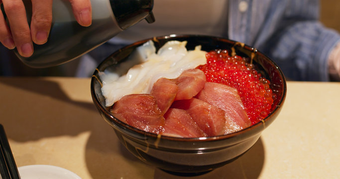 Woman having shashimi don in japanese restaurant