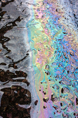 A leaked Car Oil Petrol in The Rain on a Tarmac Road Metallic Rainbow