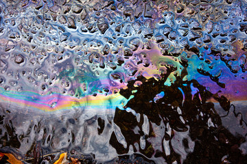A leaked Car Oil Petrol in The Rain on a Tarmac Road Metallic Rainbow