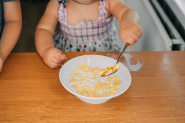 Brother and sister eat cornflakes with milk in the kitchen during the day very fun and cute, dirty and funny