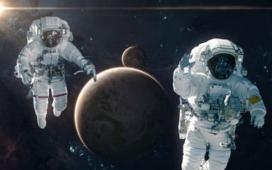 Fototapeta na wymiar Two astronauts on background of Earth and Moon. Solar system. Science fiction. Elements of this image furnished by NASA