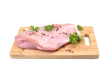 Raw turkey fillet with parsley and  spices on a wooden cutting board over white background.
