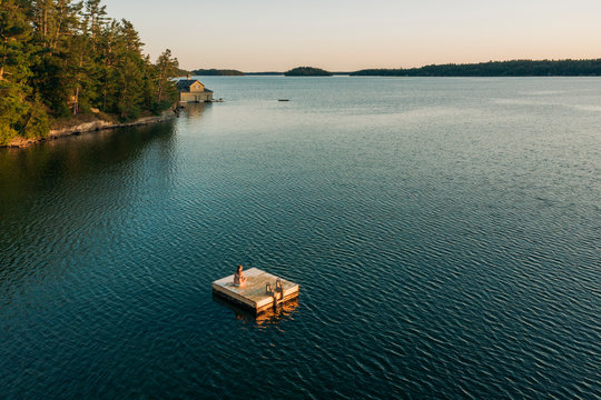 Woman Sitting On Floating Dock In Canadian Lake