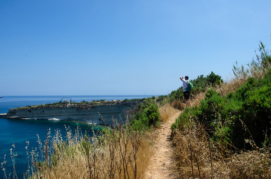 Man making photo on Munxar path. Nature with Mediterranean Sea with blue water and white rocks in Malta near Marsaxlokk, Saint Peter Pool.