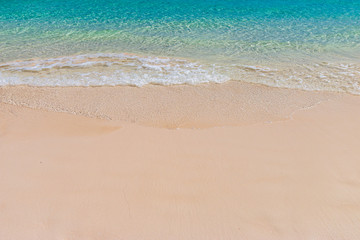 Fototapeta na wymiar Gentle ocean waves lapping onto a sandy, tropical beach. Relaxing background.