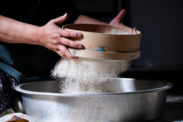 Chef woman sifting with hands, sifting flour with flour filter or sifter