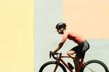 Cyclist riding bicycle against colorful wall