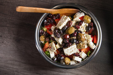 Close-up of delicious gourmet tomato and olives feta cheese salad sprinkled with herbs spices in a metal bowl. The concept of delicious and healthy vegetarian food and body detoxification