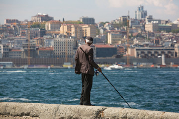 Turkey, Istanbul. Old fisherman with a fishing rod on the coast. the background of the cityscape.  fishing in the Bosphorus