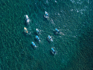 Aerial view of surfers paddling on water surface