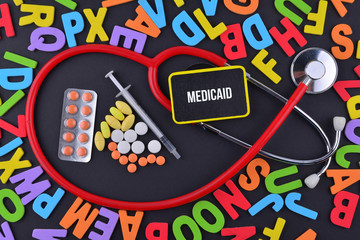 Pills, Syringe and Stethoscope with alphabet and text Medicaid