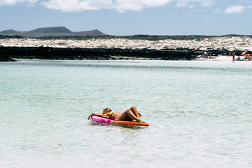 Tourism and travel lifestyle - beautiful body caucasian woman on a coloured trendy lilo enjoy the sun and the summer vacation relaxing in the transparent caribbean water of ocean