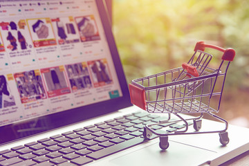 Shopping online concept - shopping cart or trolley on a laptop keyboard. Shopping service on The...