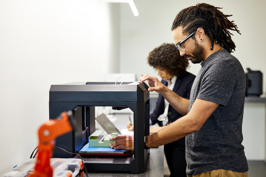 Side view of businessman examining model in 3D printer