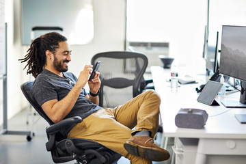 Smiling businessman using smartphone in office
