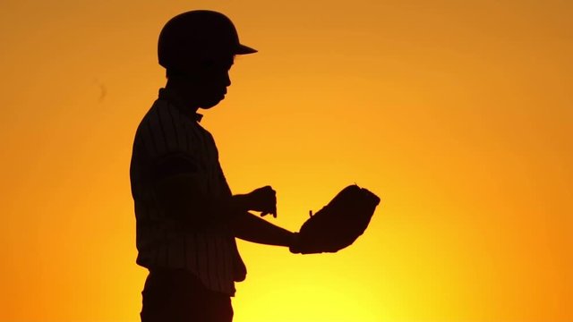 Silhouette man with a baseball glove catching a baseball footage slow motion