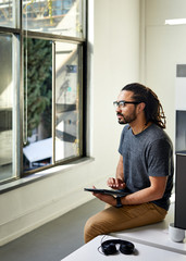Thoughtful businessman with tablet computer sitting in office
