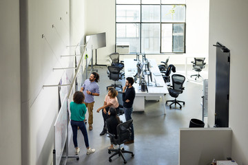 High angle view of colleagues talking over whiteboard in office