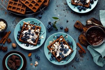 Chocolate belgian waffles with ice cream and fresh blueberry on blue background, top view